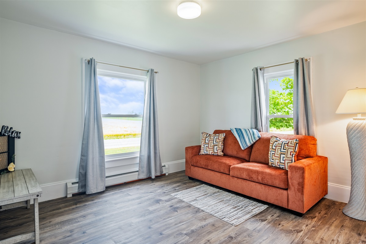 Relax in this cheerful sitting room with an eye-catching orange sofa queen size fold out sofa, two large windows, and picturesque countryside views.