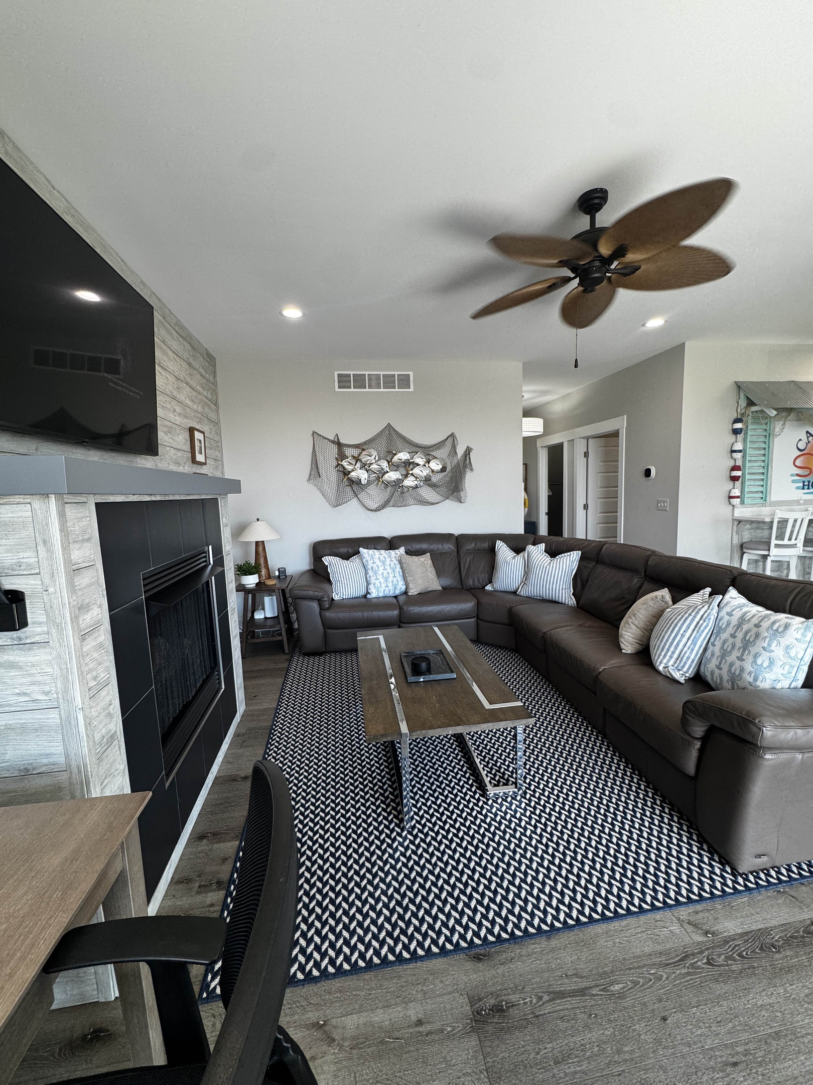 Cozy living room with a large sectional sofa, modern fireplace, and coffee table, set on a stylish patterned rug—perfect for relaxing and gathering with family or friends.