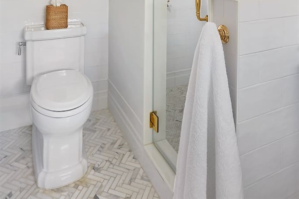 The large shower, featuring Calacatta marble herringbone floors, offers a serene, spa-like ambiance.