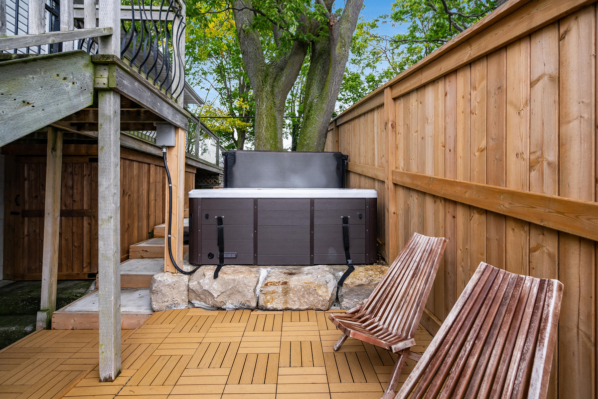 Private hot tub nestled beneath mature trees on a spacious deck.