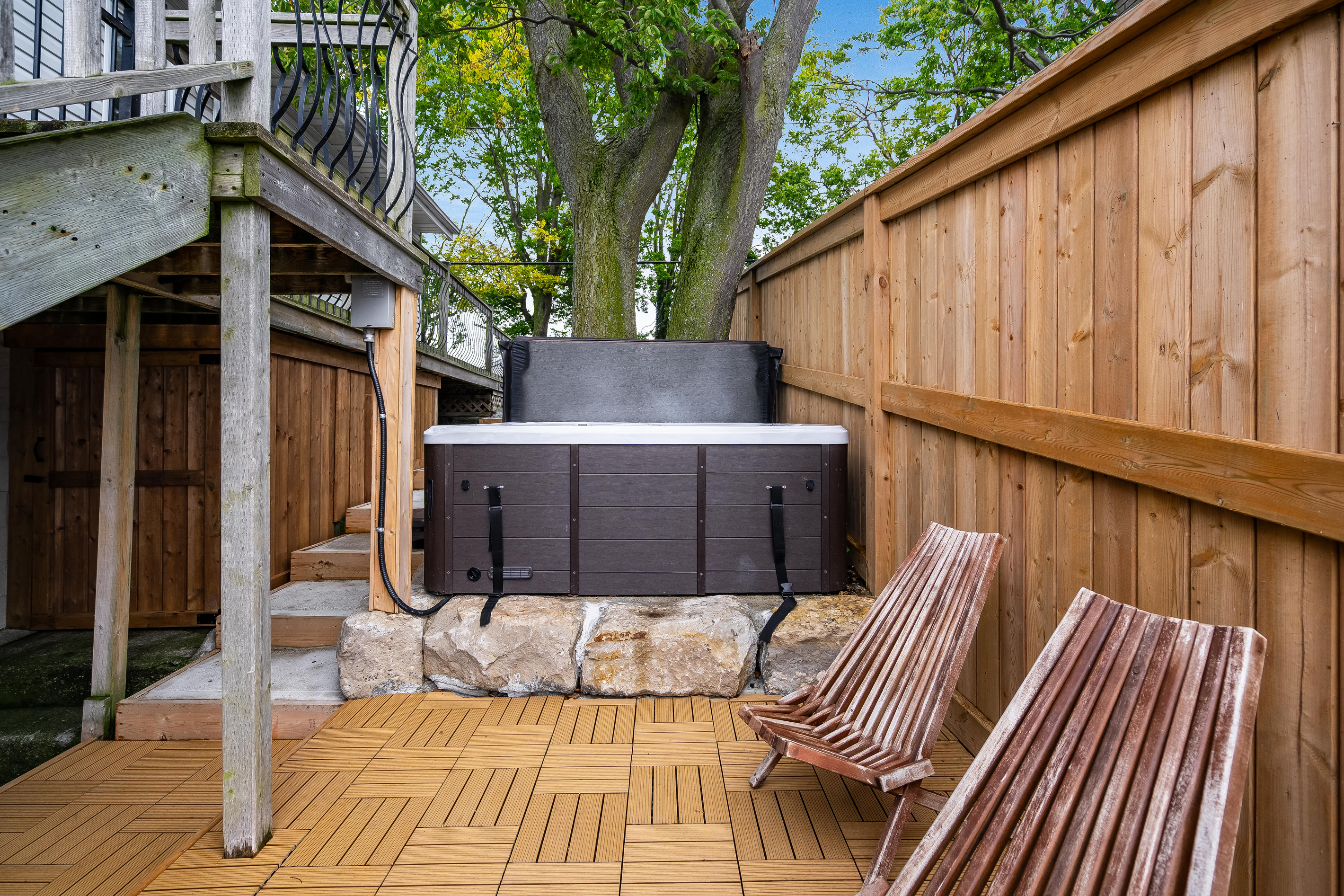 Private hot tub nestled beneath mature trees on a spacious deck.
