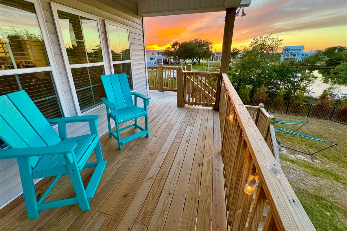 Private backyard dock with boat lift and fillet table, fenced-in backyard, fire pit with Adirondack chairs, hammocks, propane grill, picnic table, outdoor shower, expansive waterfront back deck with string lights, neighborhood boat ramp