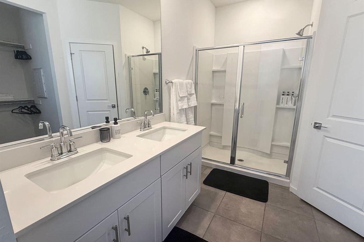 Bathroom with double vanity, mirror, and glass shower
