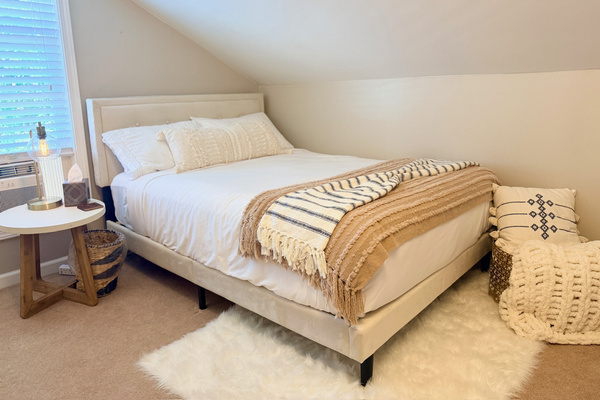 Upstairs bedroom with a double bed, soft linens, and sloped ceilings.