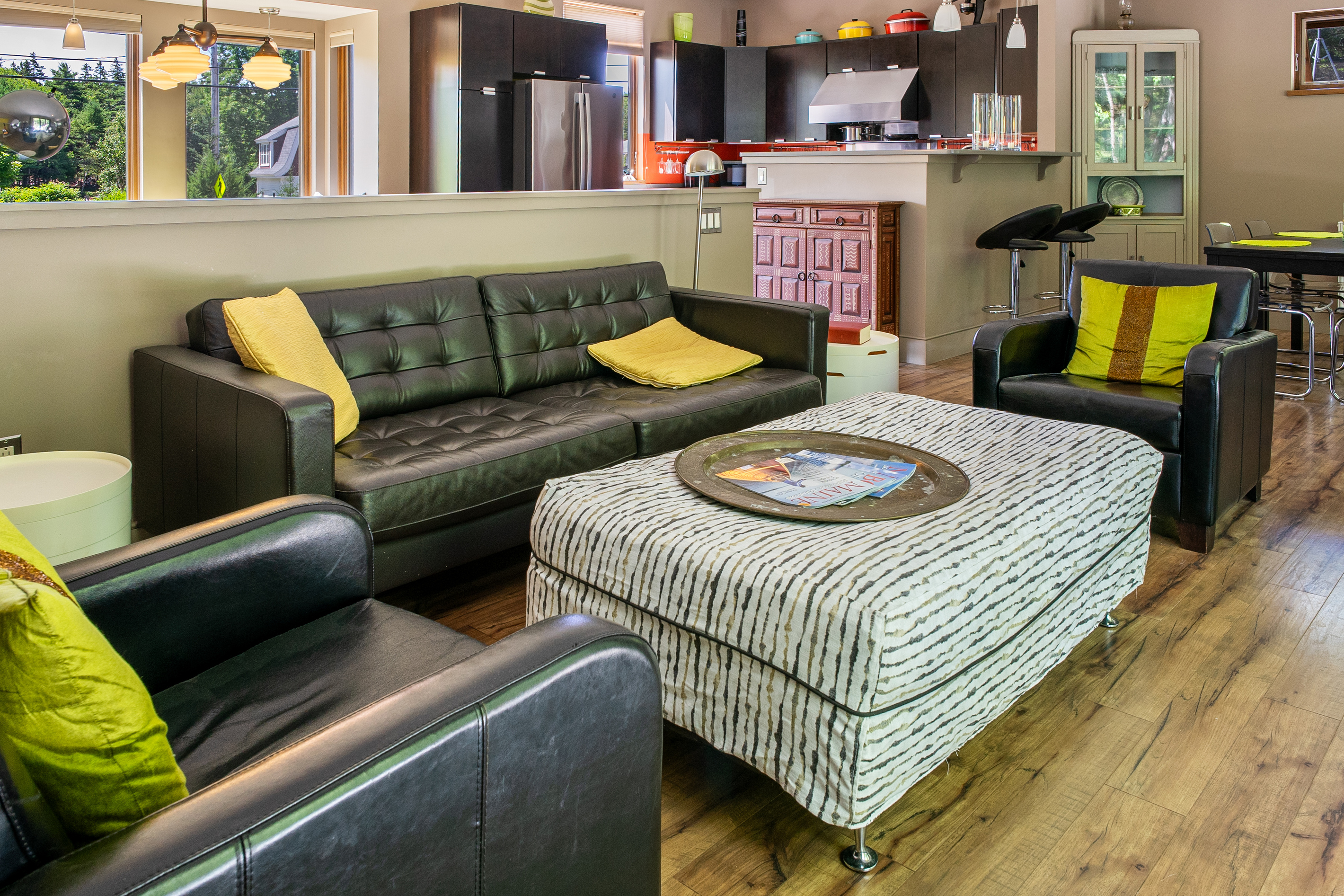 The main level sitting area features modern leather seating and intentional designer touches. Positioned directly across from a wall of windows, this space offers uninterrupted views of the 33ft deck and the quiet Acadia National Park border.