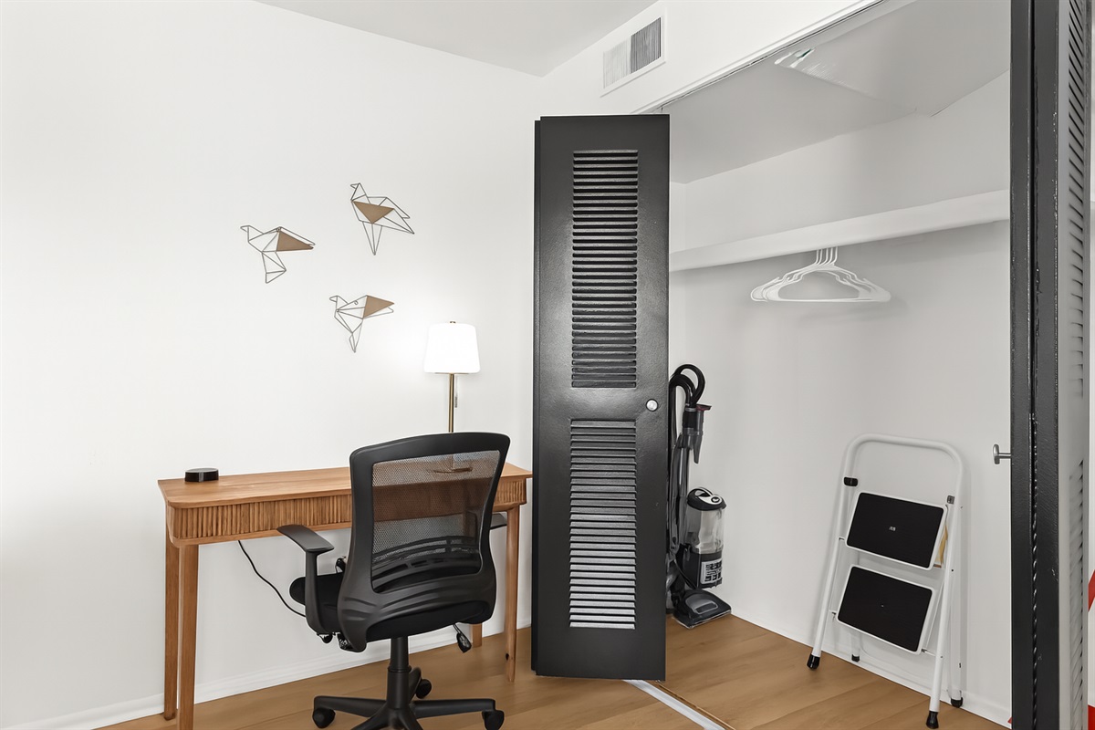 Dedicated work-from-home desk setup with comfortable seating and wall hooks for coats or bags.