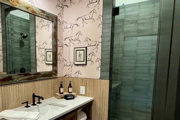  Rancher's Rest private en-suite bath — designer vanity, walk-in tile shower, modern Western finishes. Every bedroom has its own bath in your Gaines Ranch on the Square group reservation.