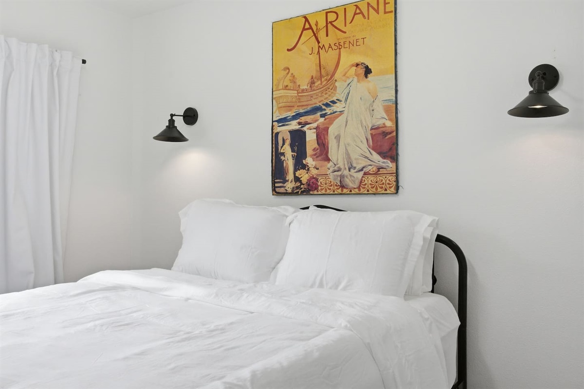 Cozy queen bedroom with stylish decor, bedside lighting, fast WiFi access, and room darkening shades for peaceful nights.