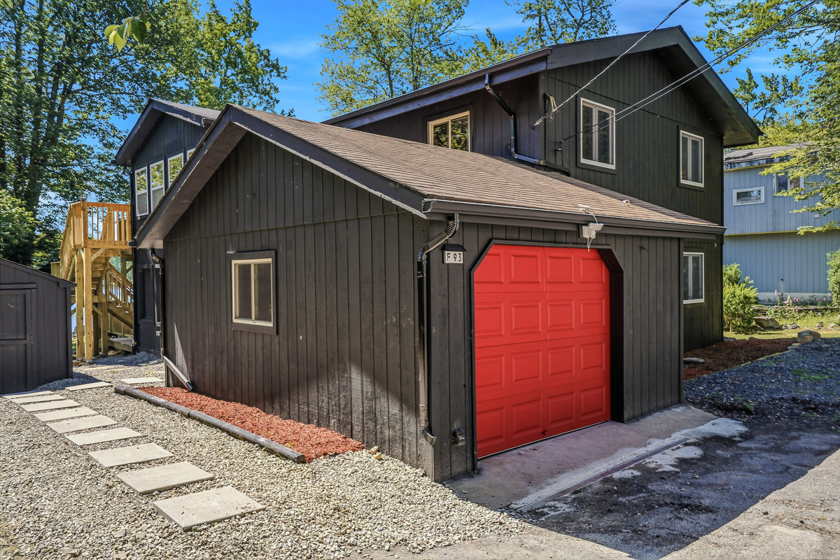 Detached garage exterior with red door and gravel driveway