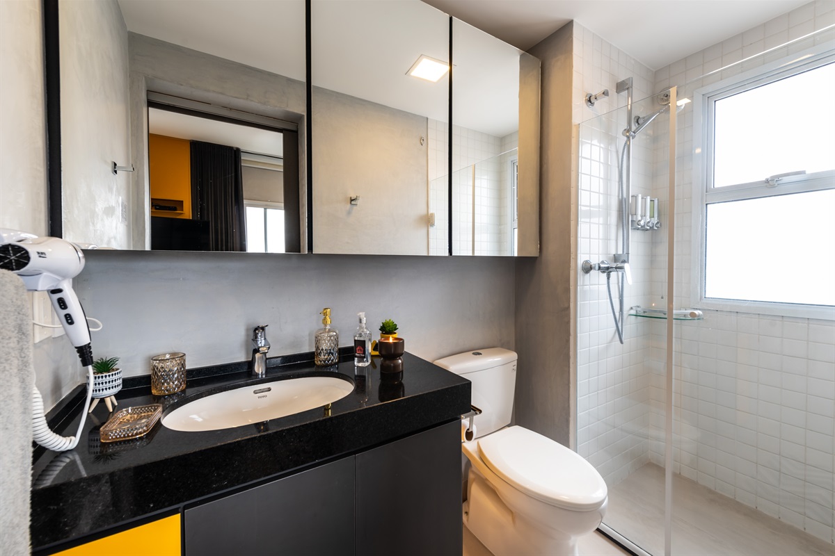 Banheiro completo e moderno em Pinheiros, com pia, vaso sanitário e box de vidro.