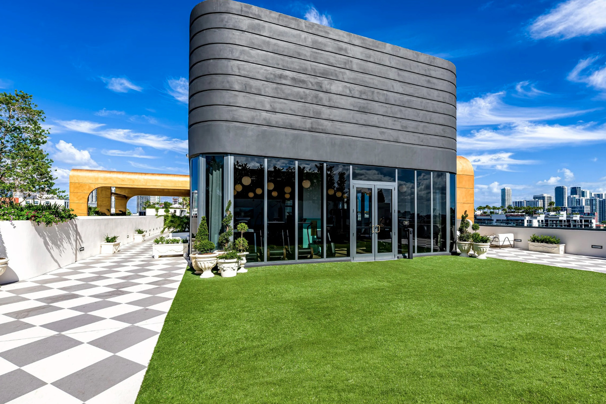 An open-air event lawn on the rooftop, framed by a graphic deck and uninterrupted skyline views.