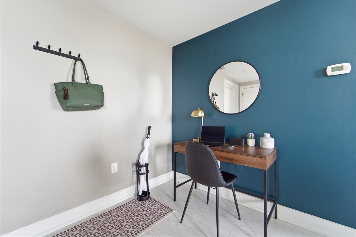 Dedicated workspace desk with pens, posted notes, desk lamp, and mini bluetooth speaker.