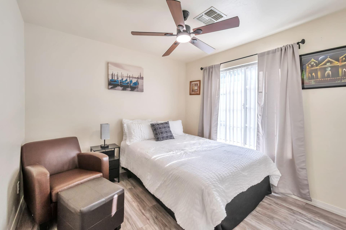 Sleep in — Bedroom 1 pairs a cloud-soft bed with a cozy reading chair and blackout curtains