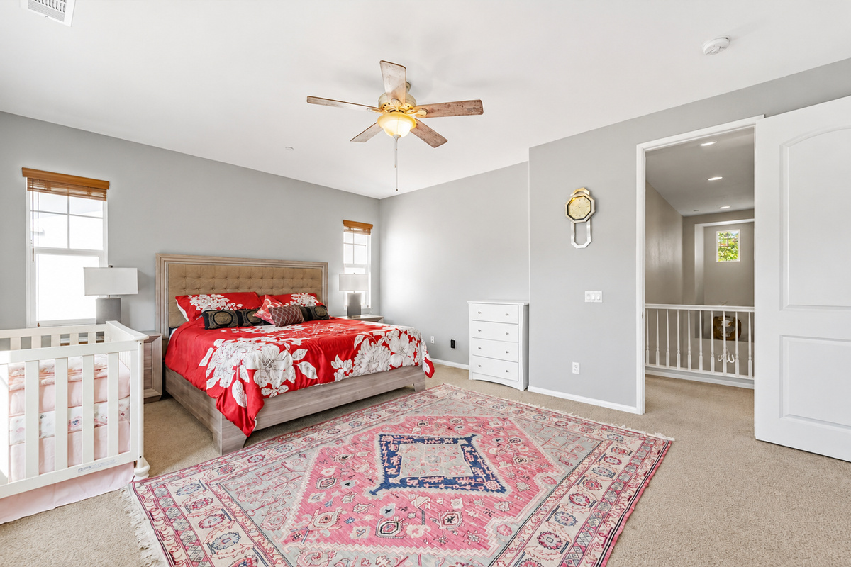 Primary bedroom with a cozy bed, ceiling fan, dresser storage, and a crib for little guests.
