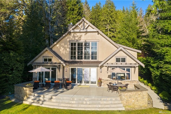 Elegant lakeside view of the home, featuring the patio and serene surroundings.