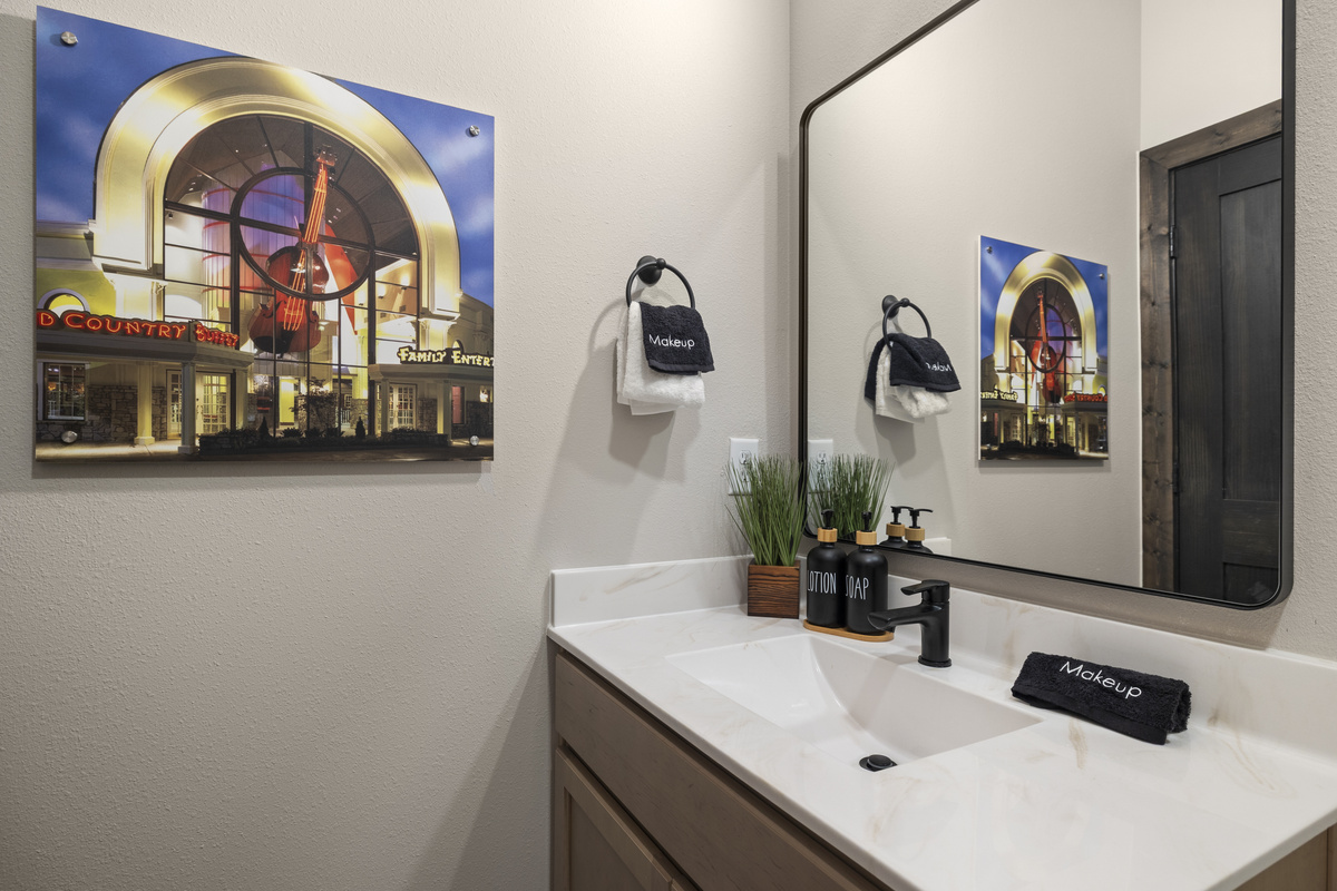 Framed theater art hangs over a black-fixture vanity.