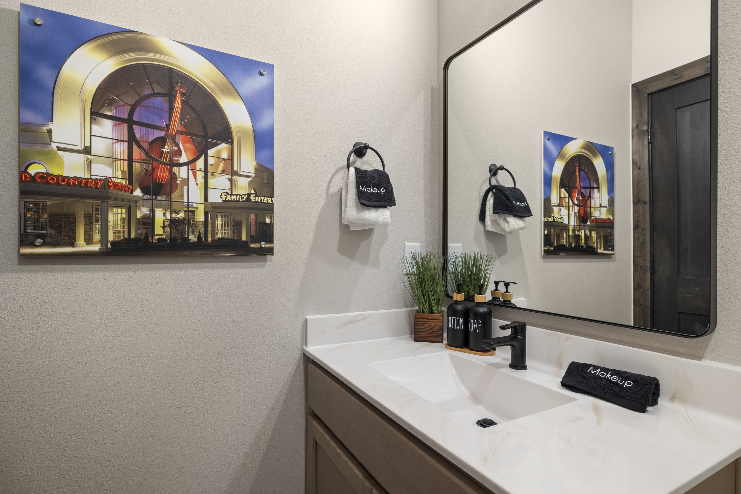 Framed theater art hangs over a black-fixture vanity.