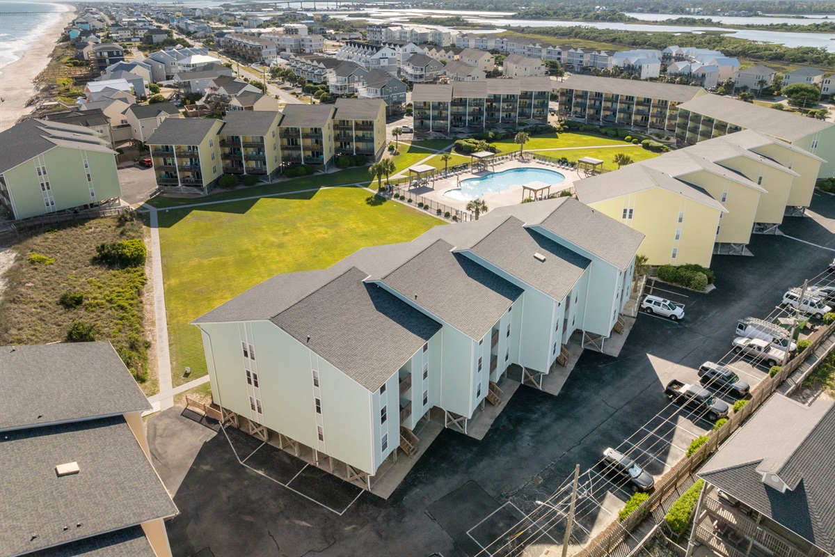 Spacious community layout with pool, green lawn, and multiple beachfront buildings