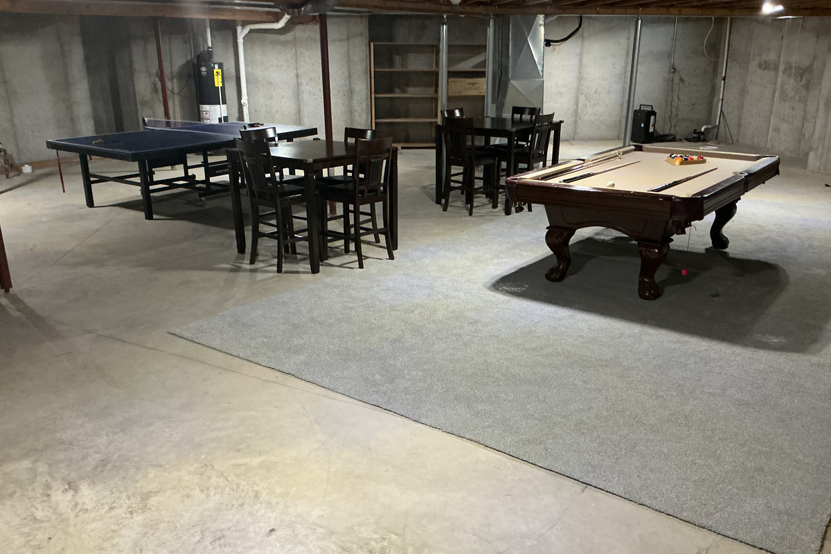 Large rec room area in basement with pool table, ping pong and two tables with chairs