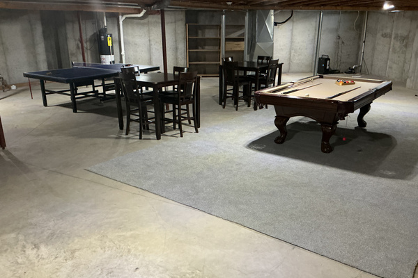 Large rec room area in basement with pool table, ping pong and two tables with chairs