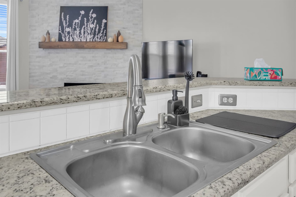 Functional kitchen setup with a double-basin sink, dishwasher nearby, and cooking essentials for effortless cleanup.