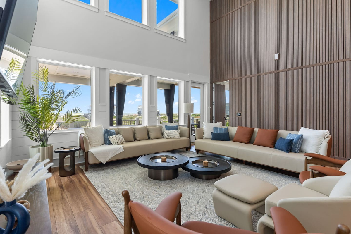 Open the door and let the ocean breeze in. With floor-to-ceiling views, a warm wood slat accent wall, and seamless access to the back deck, this space beautifully blends indoor comfort with outdoor coastal living.