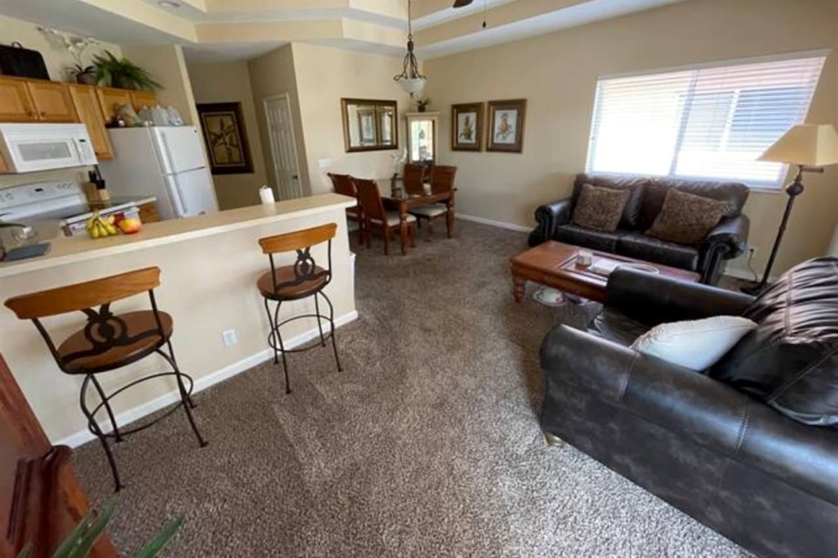 Comfortable living and dining area with cozy seating, breakfast bar seating, and large windows for natural light.