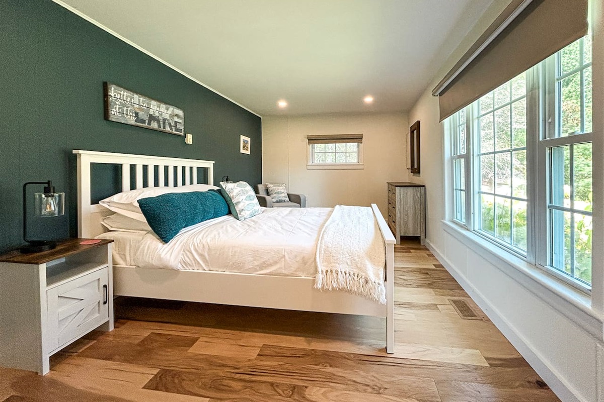 The queen bedroom is located on the ground floor, off of the great room, and has a view of the backyard and the lake in the distance