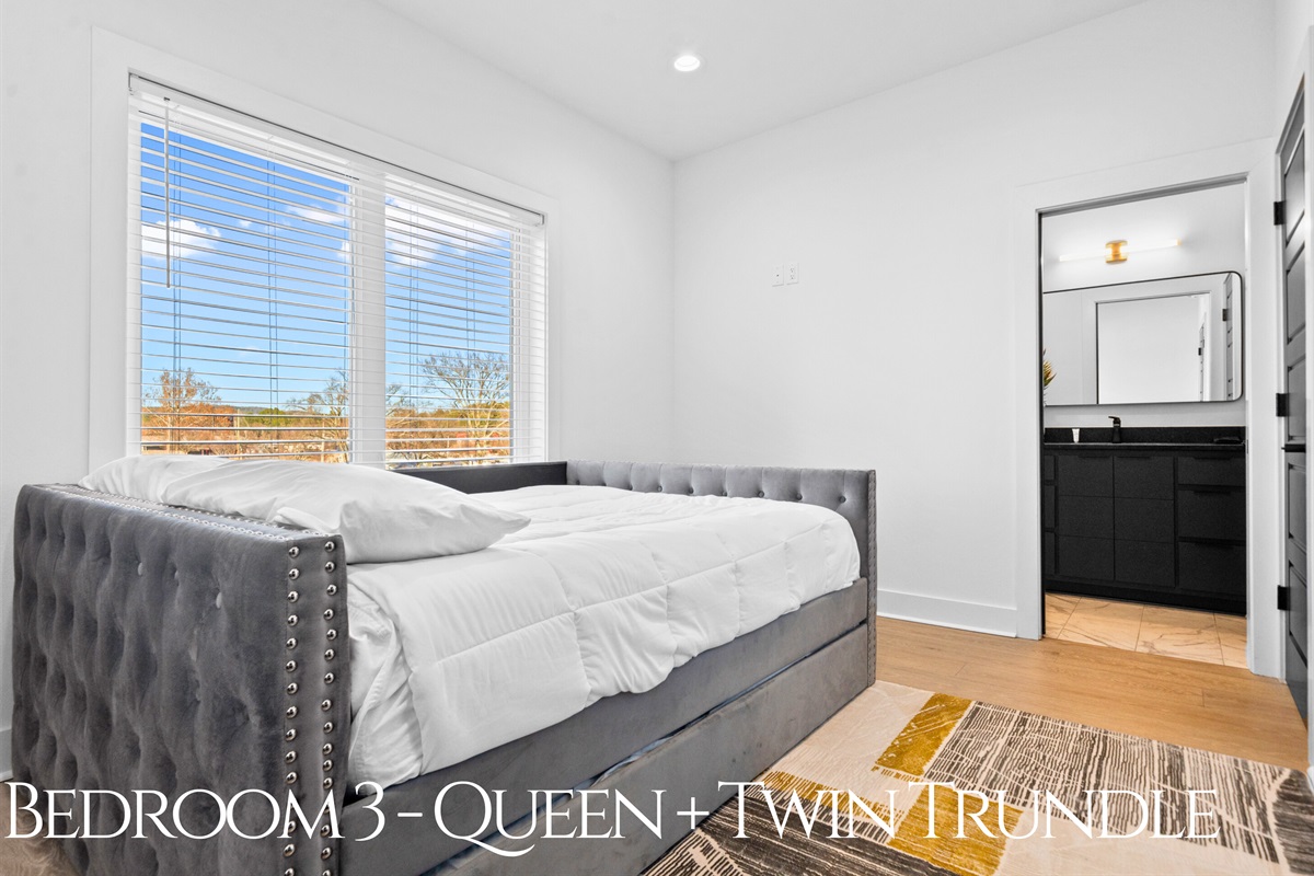 A flexible queen bedroom featuring a twin trundle, modern decor, and natural light, creating a stylish and versatile space for families or groups.