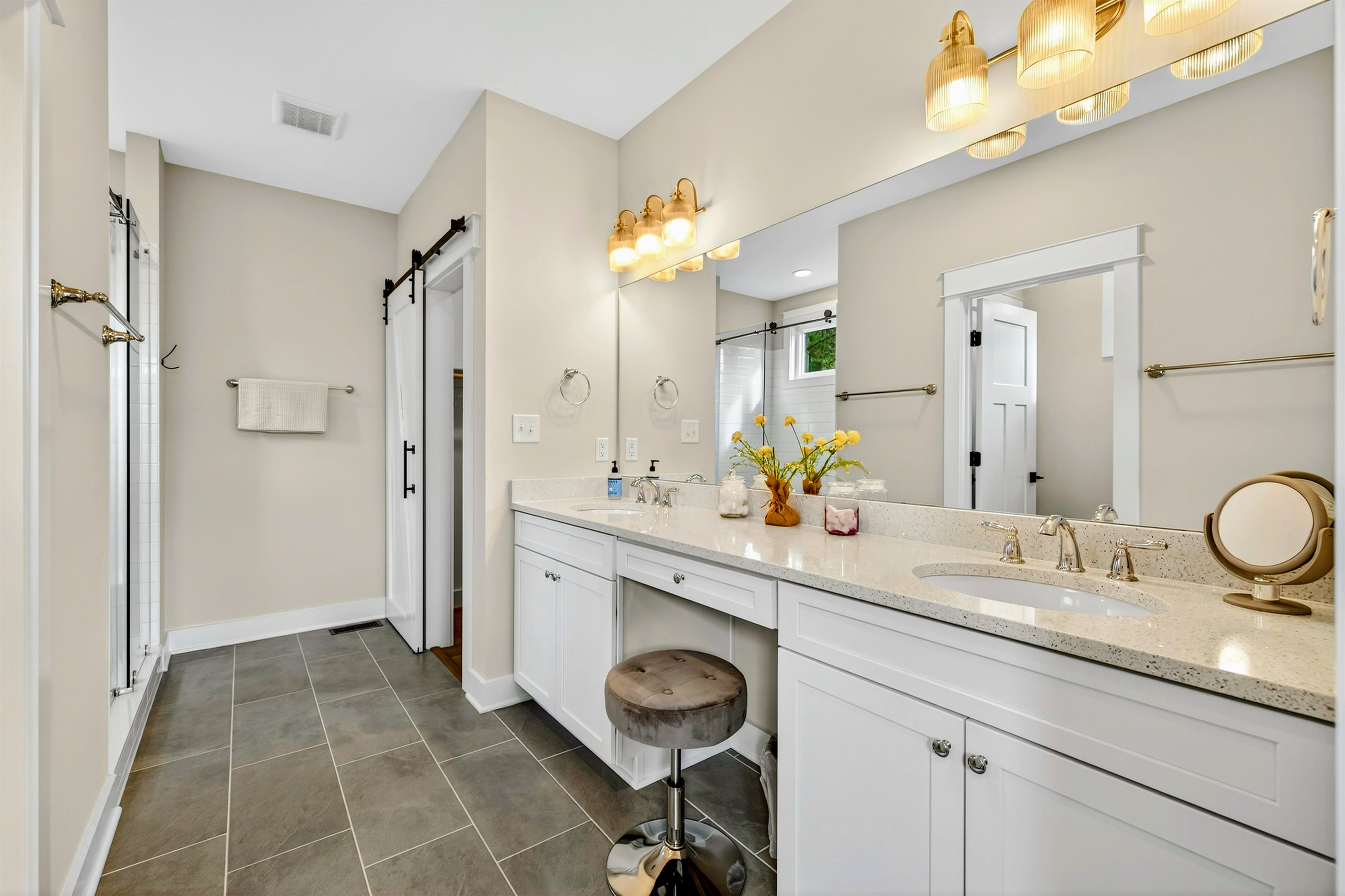 The primary suite bath has a spa vibe with light flooding in from windows in the large glass shower. Guests will love the double quartz vanity with the seated make-up area and huge walk-in closet with barn doors. SO many curated details in the master suit!