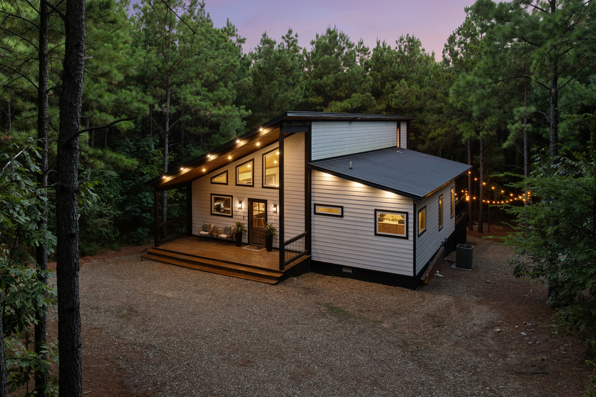 As evening settles in, the cabin lights up against the pines and turns into your own cozy hideaway in the woods.
