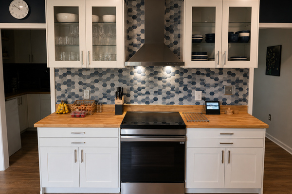 Kitchen cooking area with butcher block counters, full-size range, microwave and colorful tile backsplash.