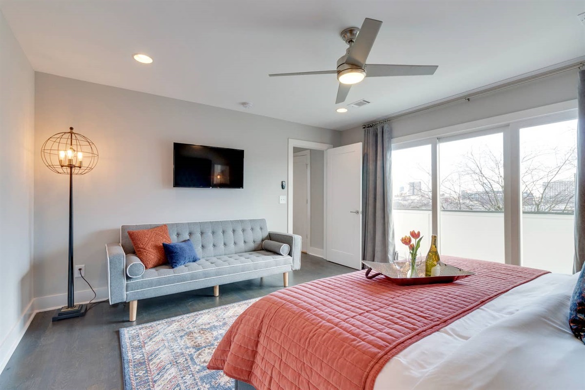 - Enjoy a movie night from the comfort of a velvet tufted futon with accent pillows - Wall mounted TV and vintage floor lamp make this corner perfect for downtime - Spacious and stylish, this bedroom offers comfort and charm in one relaxing escape