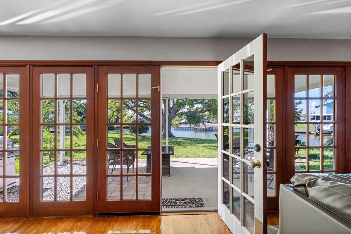 The expansive wall of French doors seamlessly connects the indoors to the outdoors, inviting greenery and sunlight into the heart of the home.