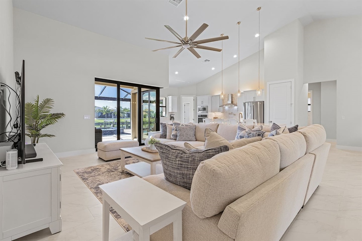 Experience the spacious coastal-designed living area featuring a large TV, easy access to the pool & spa, and stunning water views—perfect for relaxation and entertainment!