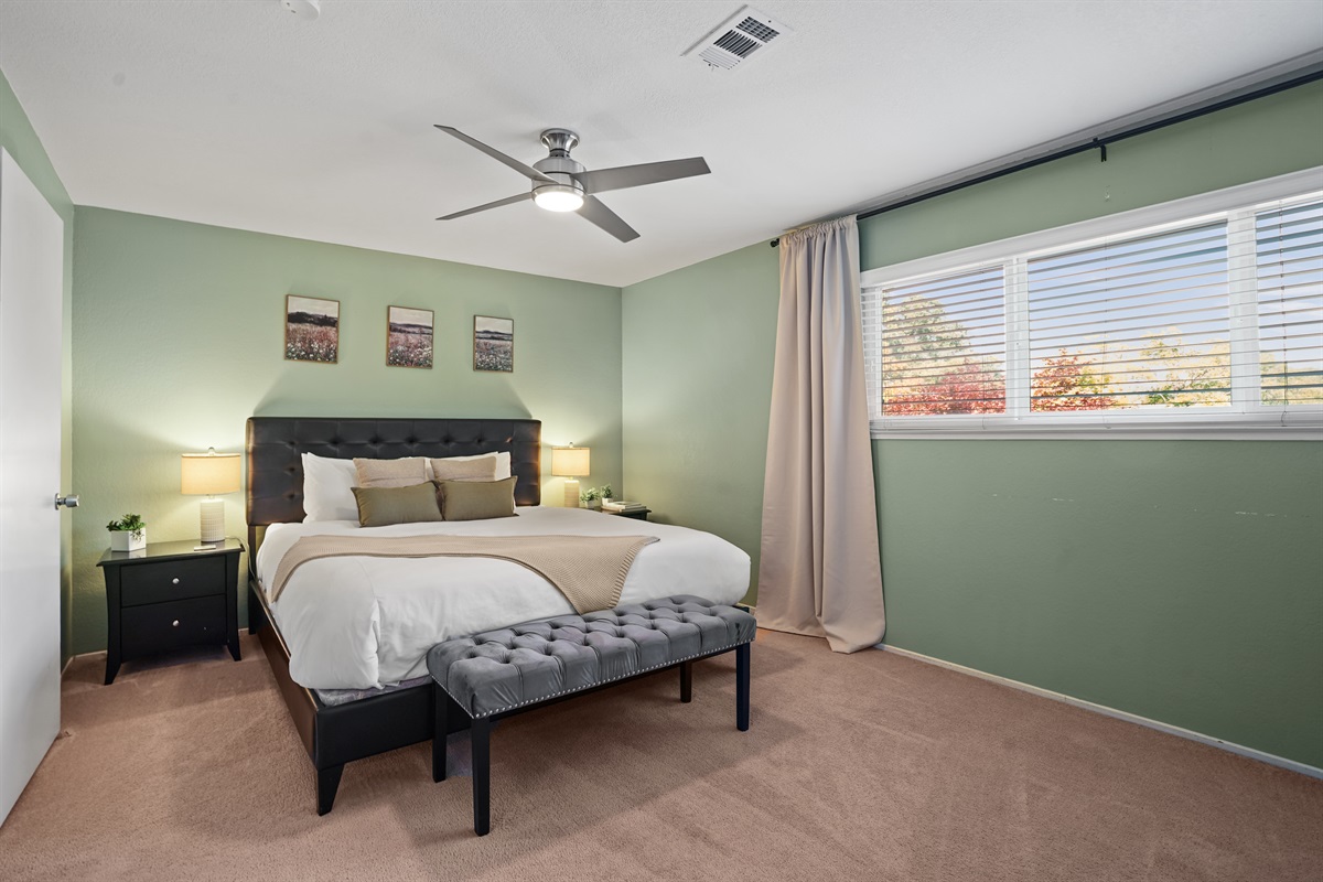 Retreat to the spacious primary bedroom featuring a plush king bed and a calm, relaxing atmosphere.