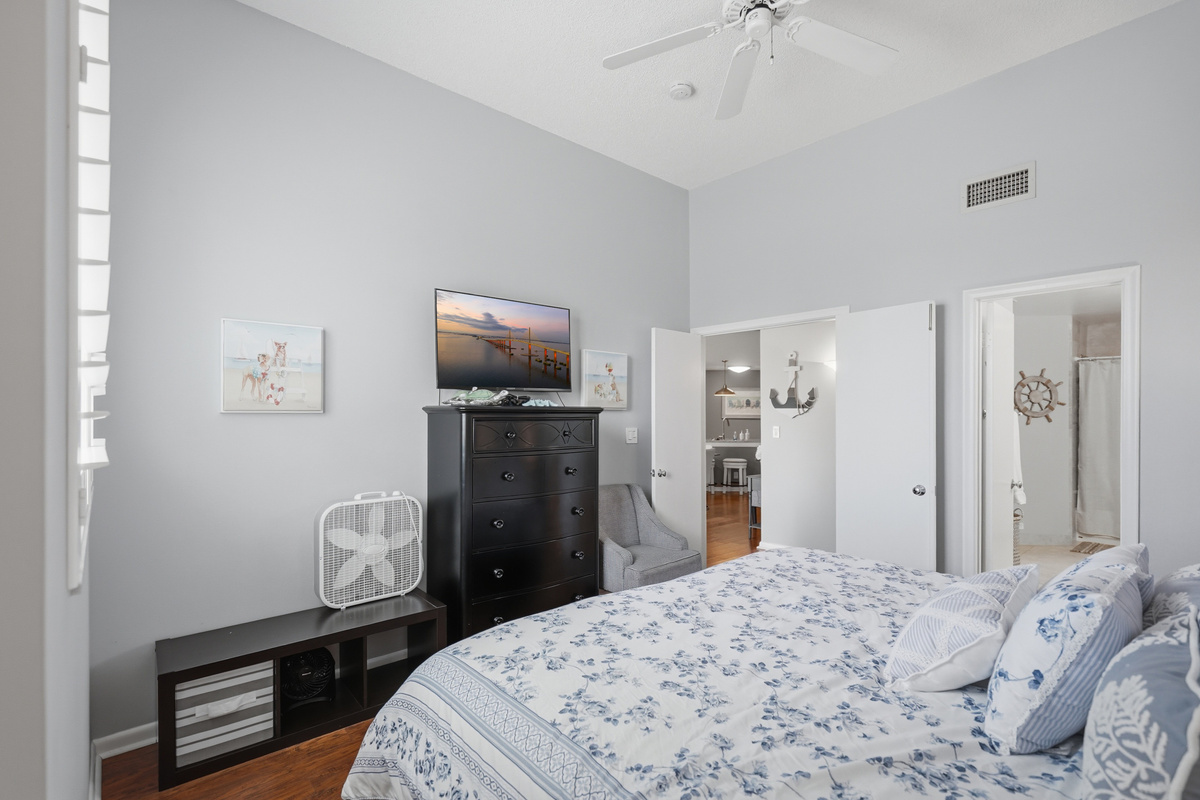 Unwind in the comfortable primary bedroom featuring a king-size bed, walk-in closet, ceiling fan, and easy access to the full bathroom. It's a peaceful retreat to relax and recharge after a day in the Florida sunshine.