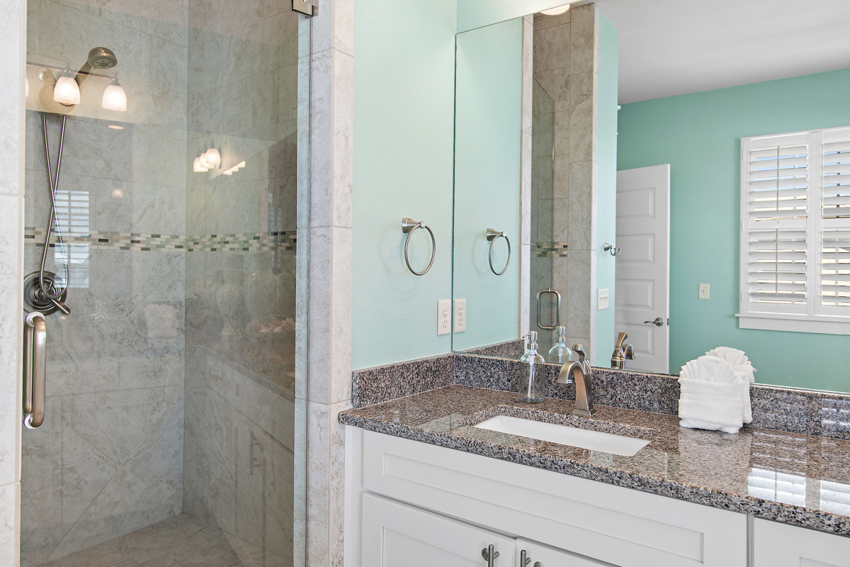 Bright, spacious bathroom with a walk in shower, generous vanity, and elegant coastal details.
