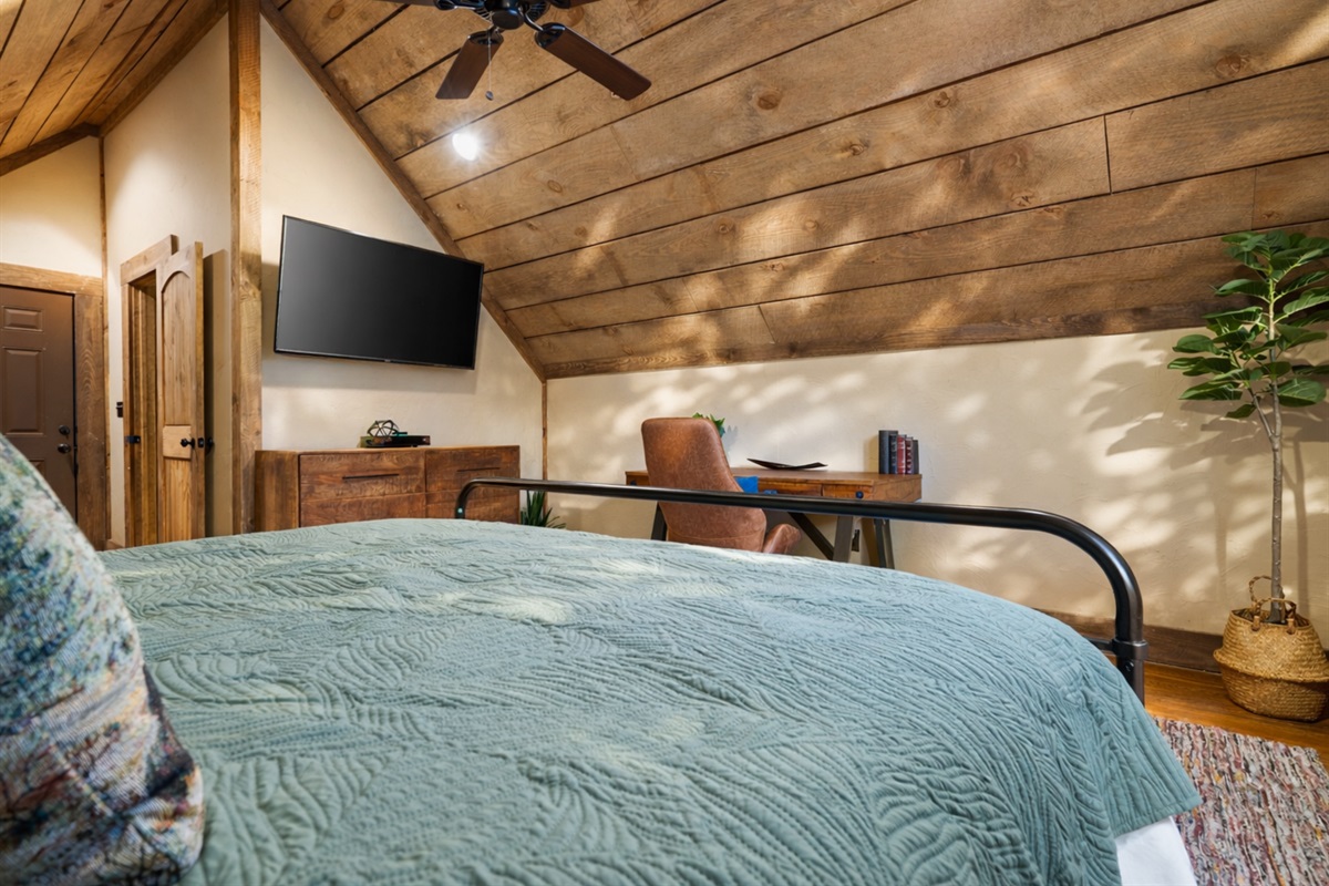 The private king suite above the garage features cozy furnishings, a smart TV, and a quiet desk nook, offering both comfort and privacy.