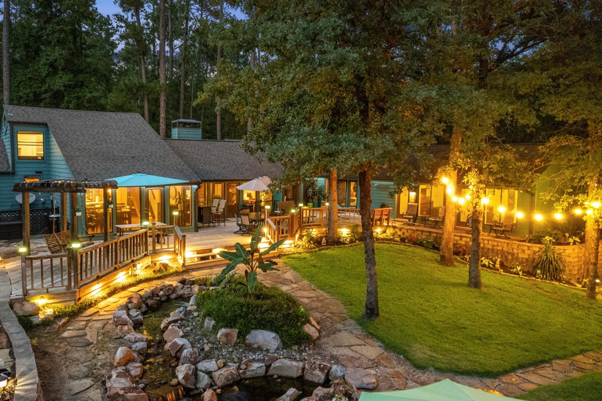 A breathtaking view of the backyard at night! With glowing string lights, a peaceful water feature, and inviting decks, this beautifully lit space creates the perfect ambiance for relaxation and outdoor gatherings.