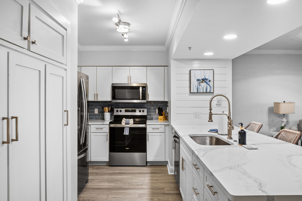 Whip up meals in this fully equipped kitchen featuring stainless steel appliances, beautiful countertops, and coastal charm, perfect for enjoying beachside breakfasts or sunset dinners at your Panama City Beach getaway.