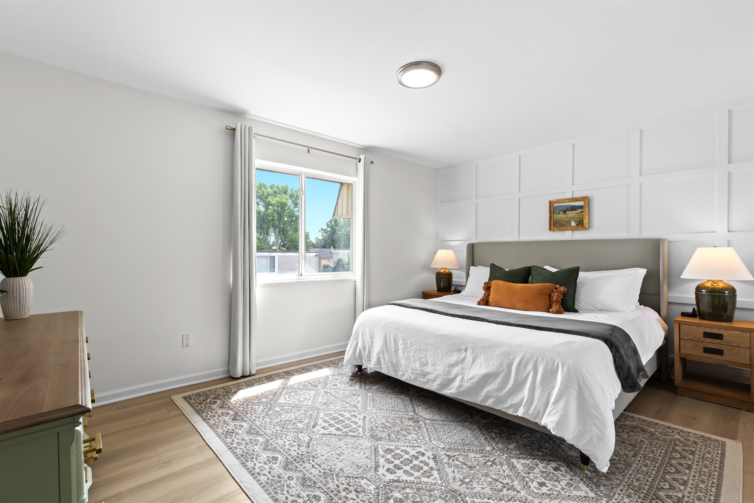 Relax in a cozy bedroom with a soft bed, neutral tones, and ample sunlight.