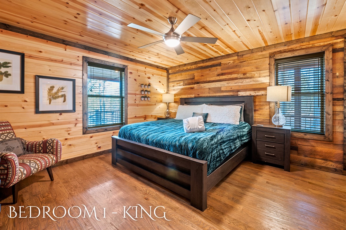 This bedroom showcases a king-sized bed with vibrant turquoise bedding and eclectic decor against a backdrop of rich wood paneling and natural lighting.
