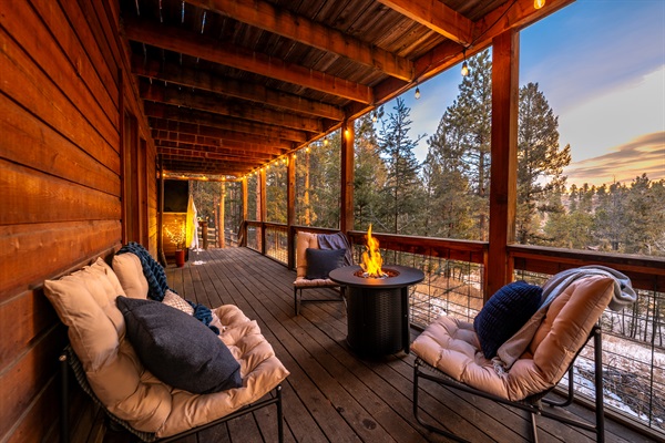 🌅🔥 Golden-hour deck vibes—string lights ✨, cushy lounge chairs, and a glowing fire table with sweeping pine views 🌲 Perfect for sunset sips and cozy nights outside 🥂