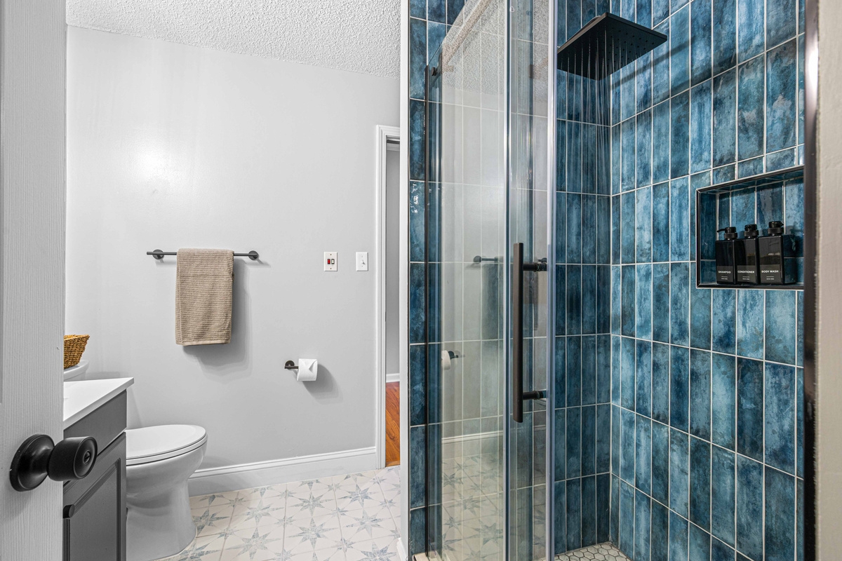 Bathroom Oasis: Refresh in style with a spacious shower and sleek blue tile accents!