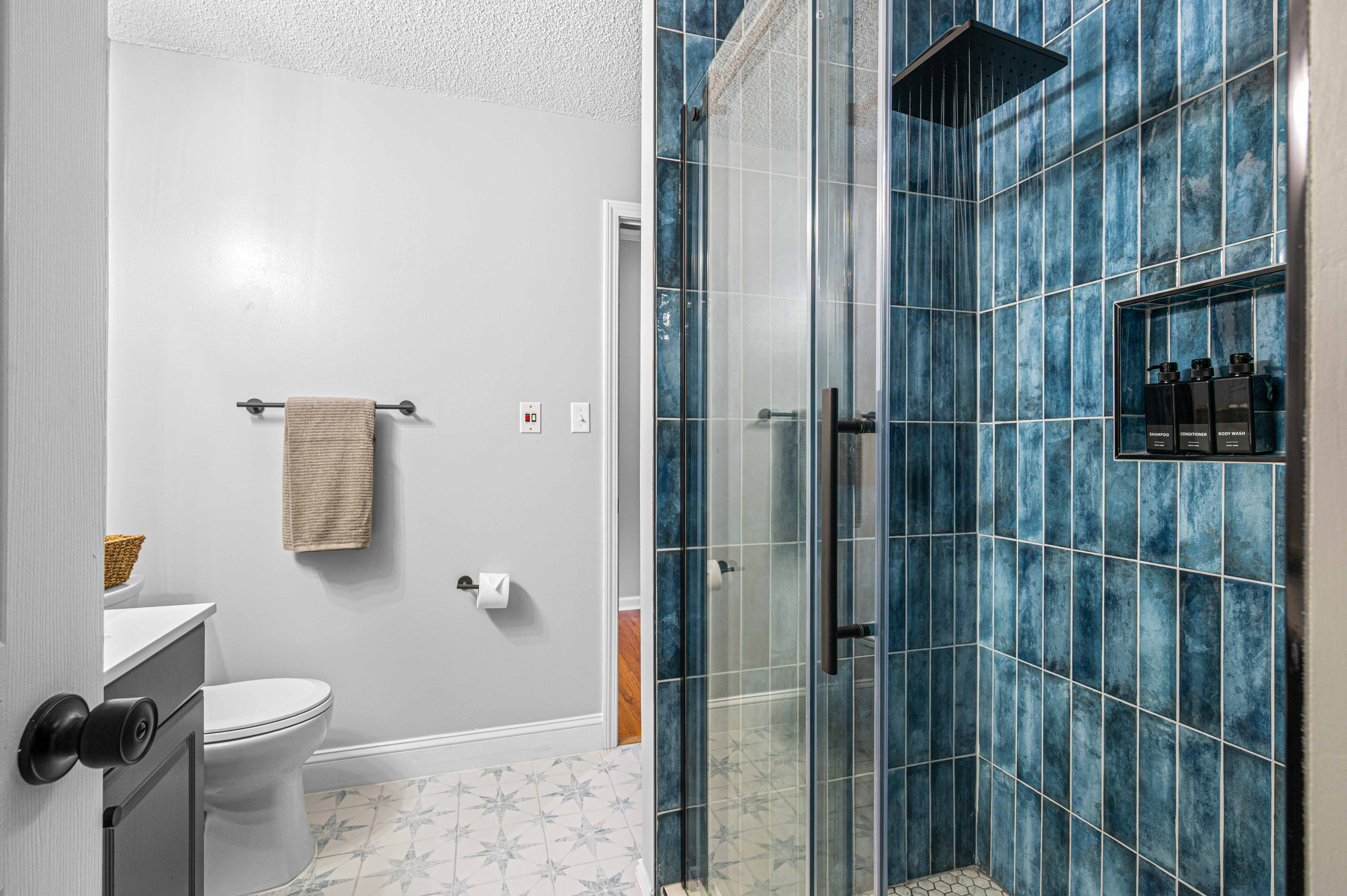 Bathroom Oasis: Refresh in style with a spacious shower and sleek blue tile accents!