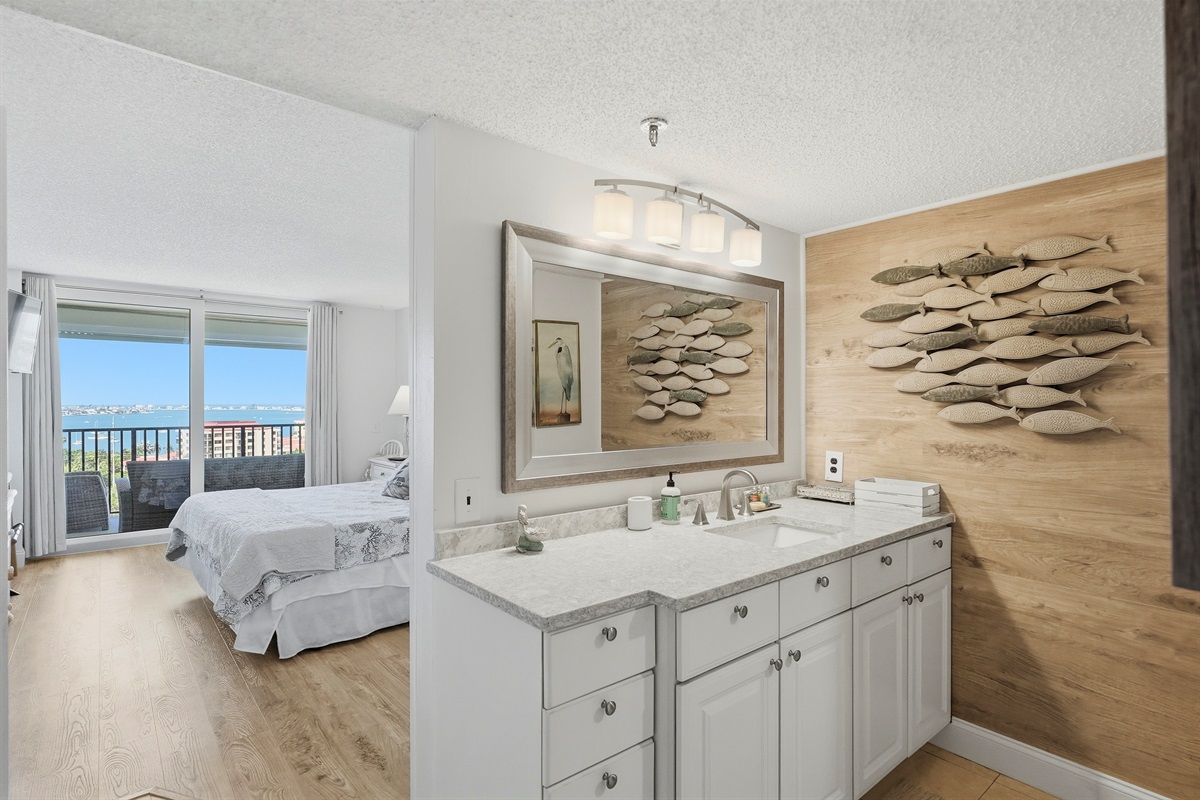 The master bedroom features a king-sized bed and a calming atmosphere, perfect for relaxing after a day at the beach or exploring the city. It offers stunning Boca Ciega Bay views with sunrise and sunset, abundant natural light, and a private en-suite bath