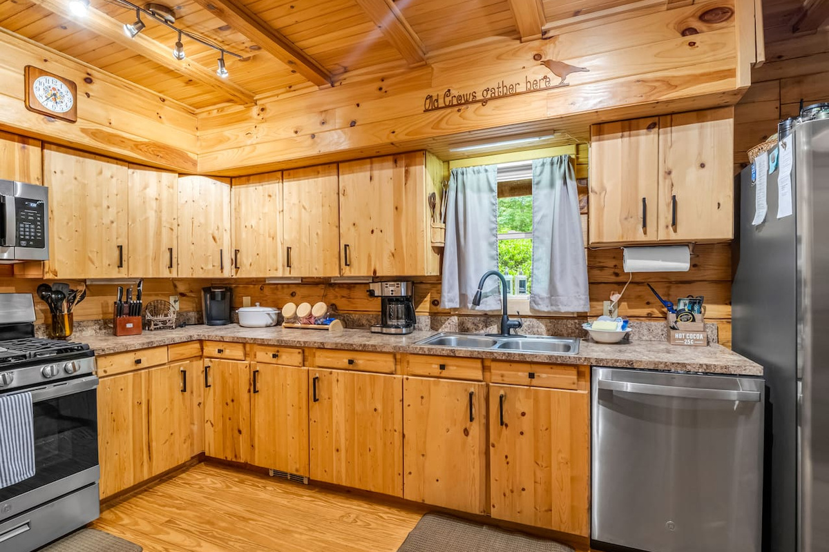 Fully equipped kitchen featuring stainless steel appliances, ample counter space, coffee area, and rustic charm