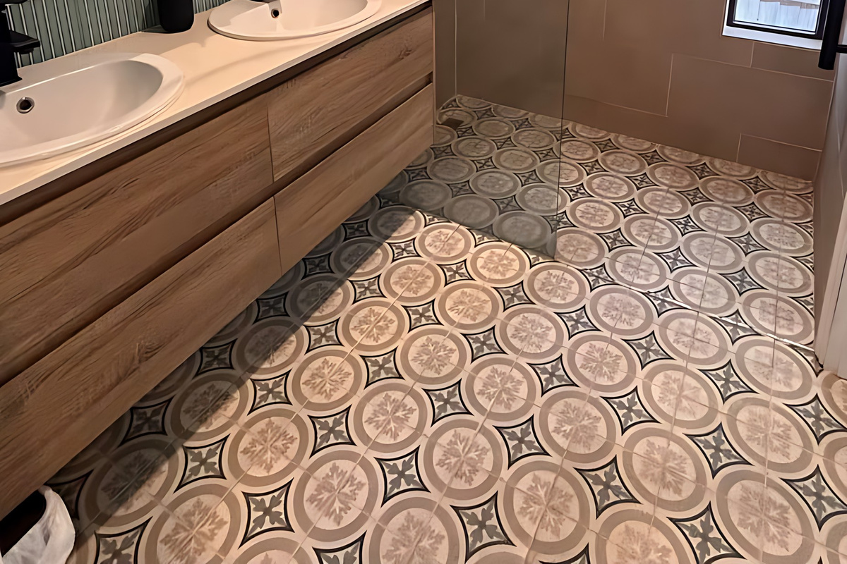 The ensuite to Bedroom 1 has a walk-in rain shower, a double vanity with twin basins, a round mirror, black tapware and patterned floor tiles, with body wash, shampoo and conditioner dispensers.