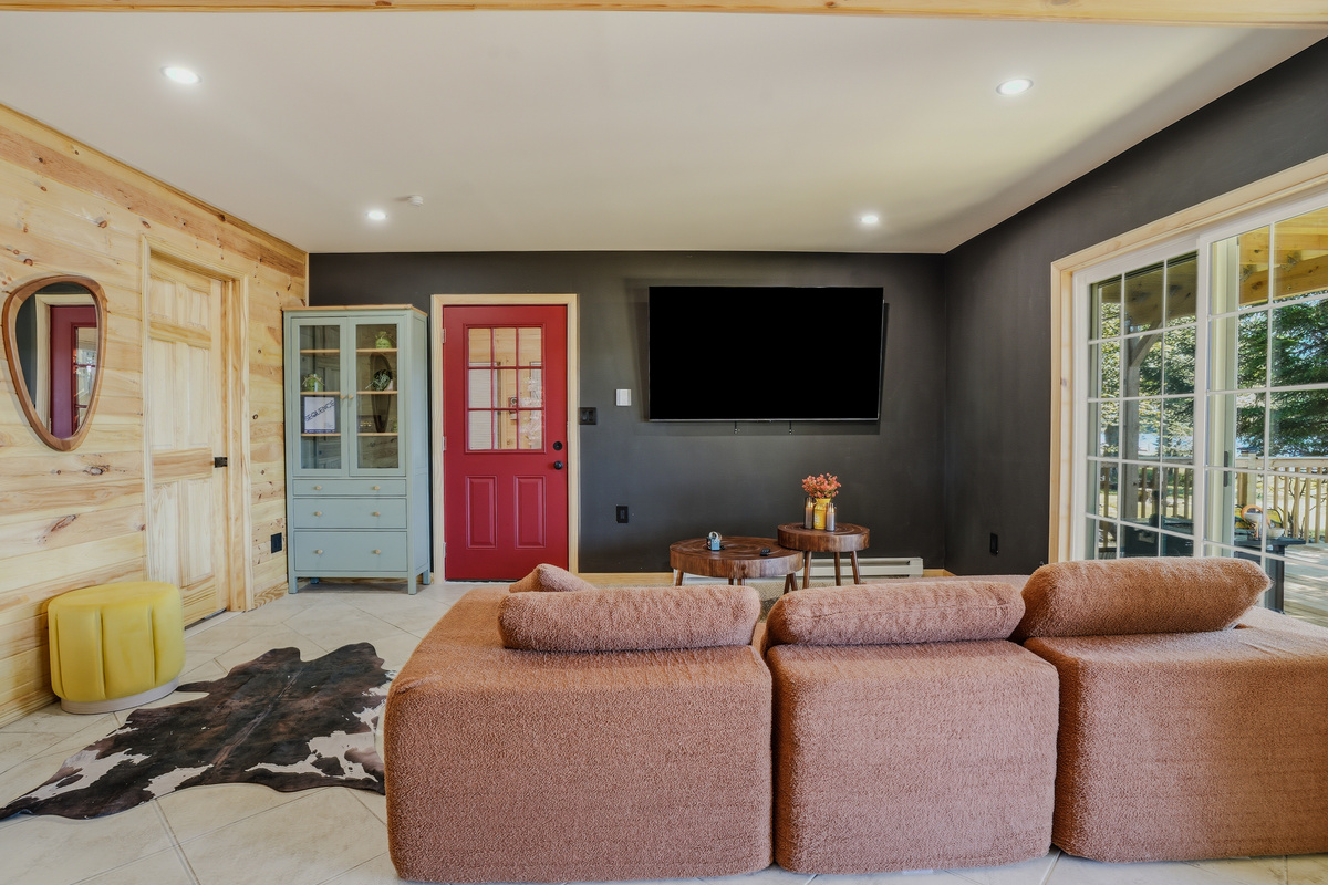 Family living/game area with sectional, flat-screen TV, and red accent door